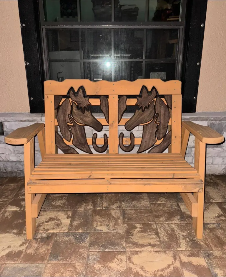 Wooden outdoor bench with horse-shaped back panels on a paver patio.