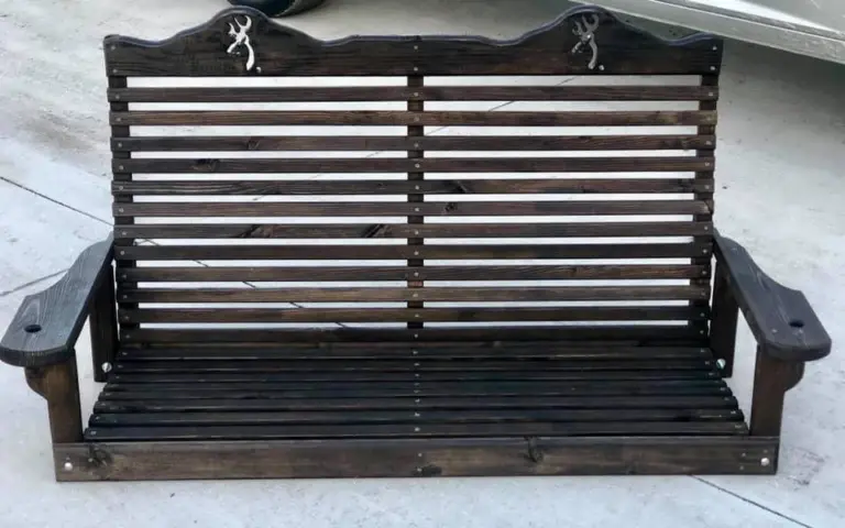 Dark wooden swing bench with a slatted back, wide armrests, and decorative deer emblems.