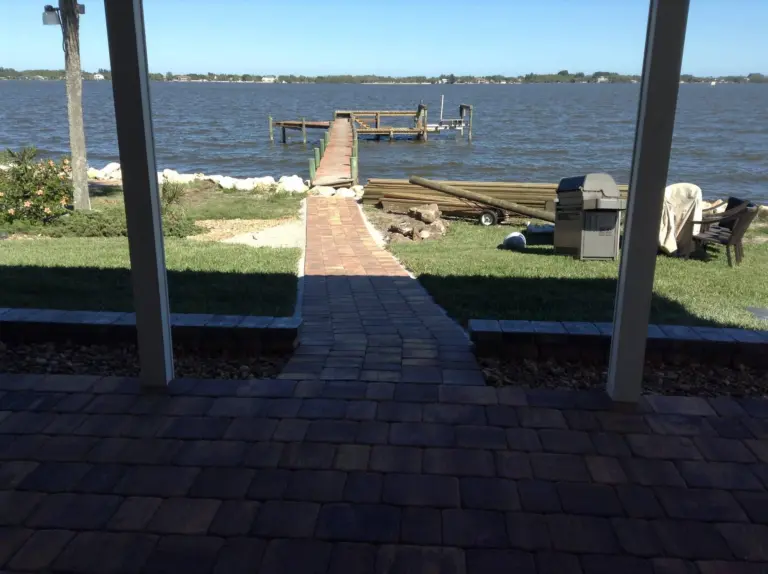 Paver path connecting a patio and lawn to a wooden pier.