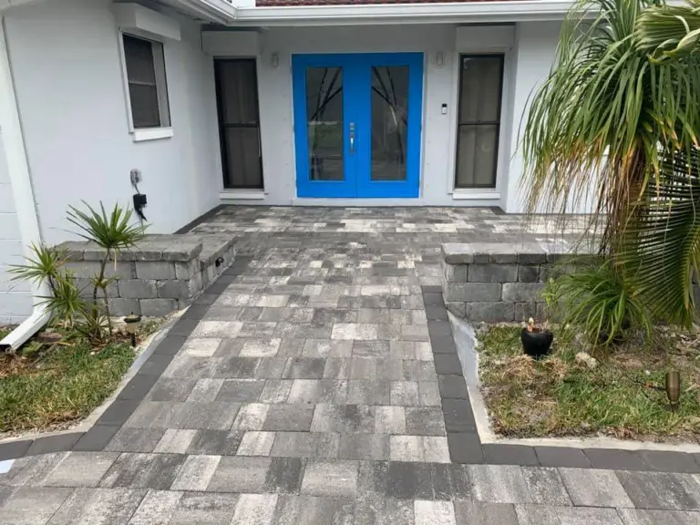 Straight gray paver approach with dark borders leading to blue double front doors.